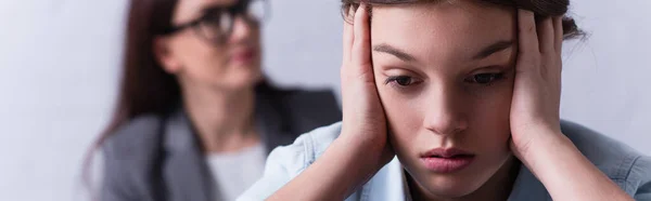 Depressed teenage girl near psychologist on blurred background, banner — Stock Photo