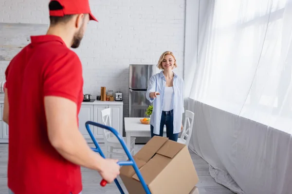 Joyful woman pointing at arabian man with trolley on blurred foreground — Stock Photo