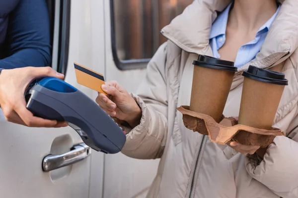 Teilansicht einer Frau mit Kreditkarte und Coffee to go in der Nähe von Kurier mit Zahlungsterminal — Stockfoto