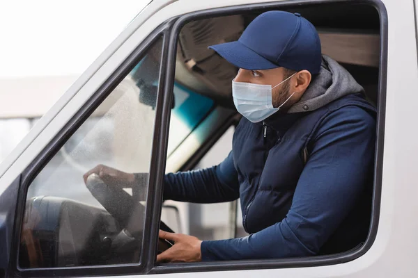 Арабський чоловік доставки в медичній масці дивиться вперед під час водіння вантажівки — стокове фото