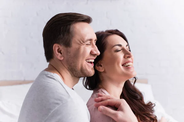 Rire homme avec les yeux fermés étreignant femme dans la chambre — Photo de stock