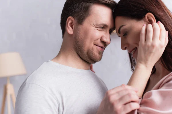 Hombre adulto sonriendo mientras mira a su esposa en casa - foto de stock