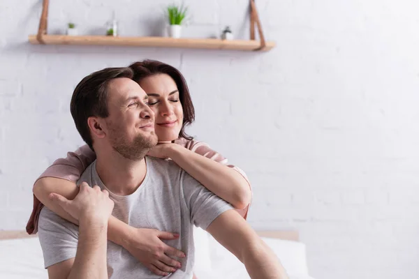 Mulher morena abraçando marido sorridente no quarto — Fotografia de Stock