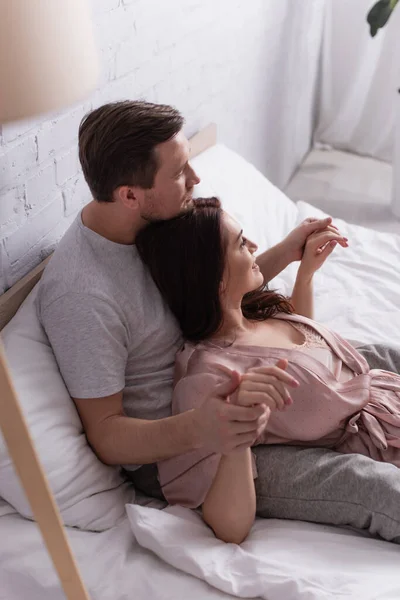 Adult couple touching hands on bed in morning — Stock Photo