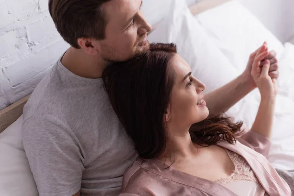 Erwachsenes Paar hält Händchen auf verschwommenem Hintergrund im Bett — Stockfoto