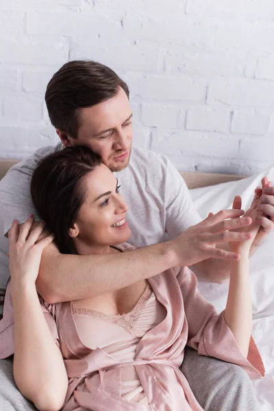 Erwachsenes Paar blickt auf Hände, während es im Bett liegt — Stockfoto