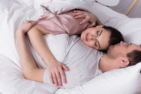 Дорослий чоловік обіймає дружину, лежачи на ліжку — стокове фото