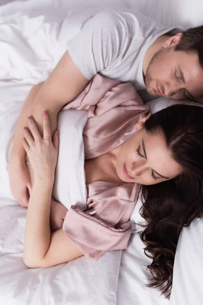 Top view of woman in pajama sleeping with husband on bed — Stock Photo