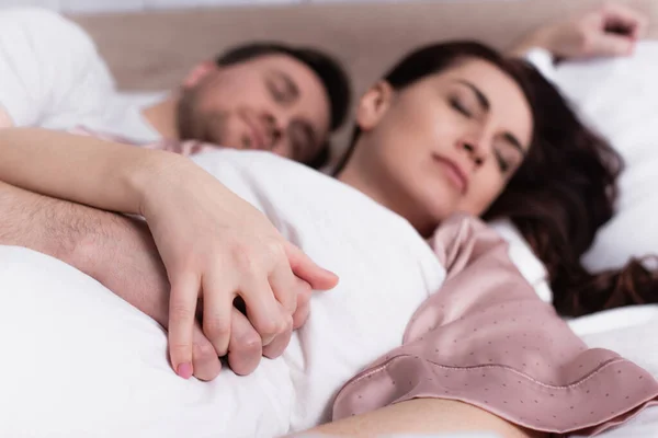 Adult couple holding hands while sleeping on blurred background — Stock Photo