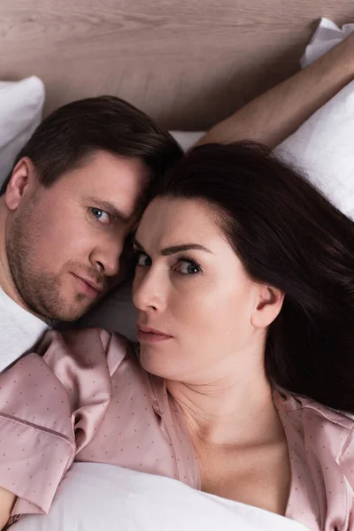 Hochwinkelaufnahme eines erwachsenen Paares, das die Kamera auf dem Bett anschaut — Stockfoto