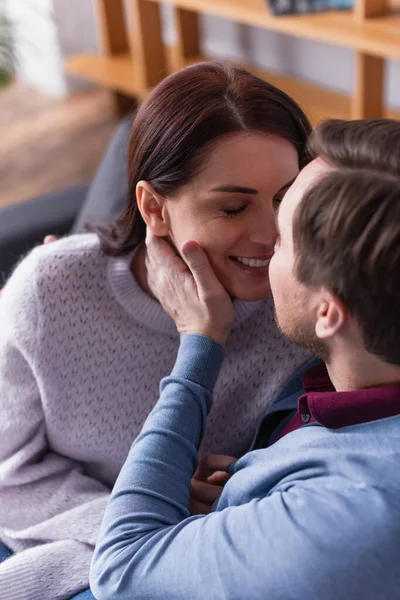 Чоловік торкається обличчя усміхненої дружини на дивані — стокове фото