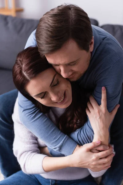 Hombre abrazando feliz morena esposa en casa - foto de stock