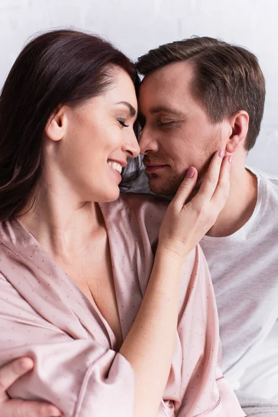 Homem de olhos fechados abraçando a esposa sorridente em casa — Fotografia de Stock