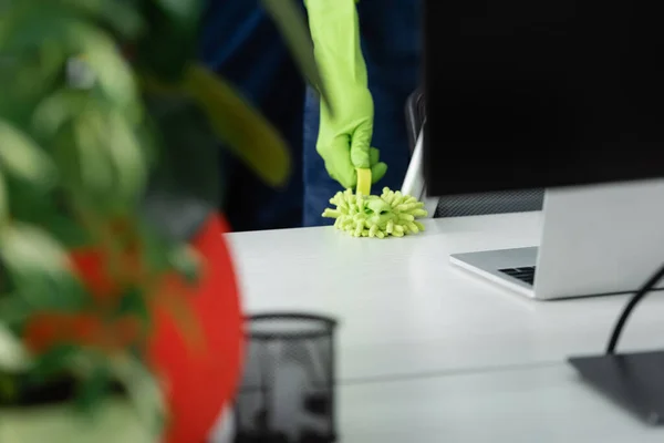 Cropped view of cleaner cleaning table with brush near computers in office — Stock Photo