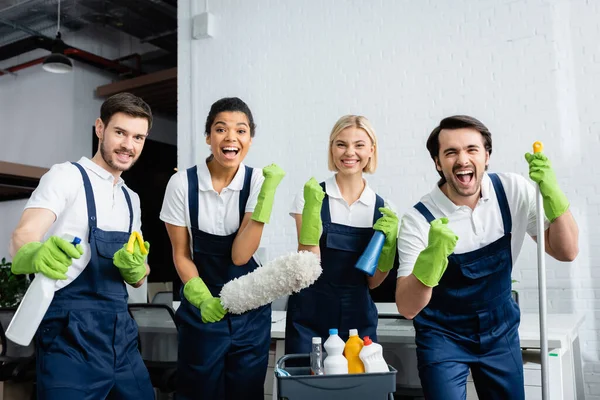 Emocionados limpiadores interracial mostrando sí gesto en la oficina - foto de stock
