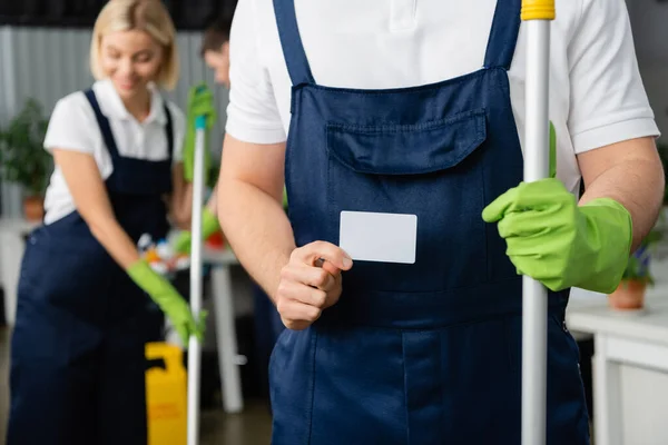 Tarjeta con espacio de copia en mano de limpiador con fregona en la oficina - foto de stock