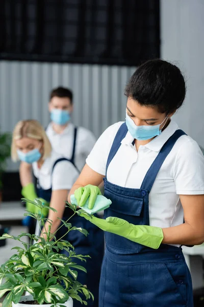 African american cleaner in medical mask cleaning plant in office — Stock Photo