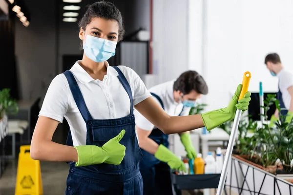 African american worker of cleaning company with mop showing like sign in office — Stock Photo