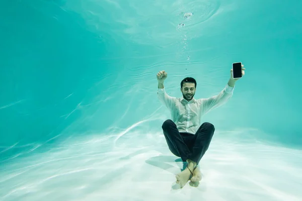 Homme d'affaires arabe joyeux avec smartphone montrant oui geste sous-marin — Photo de stock
