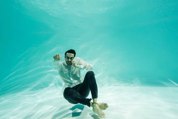 Muslim businessman in goggles talking on mobile phone in swimming pool — Stock Photo