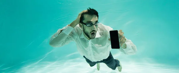 Homme d'affaires musulman étonné tenant son téléphone portable tout en nageant dans la piscine, bannière — Photo de stock