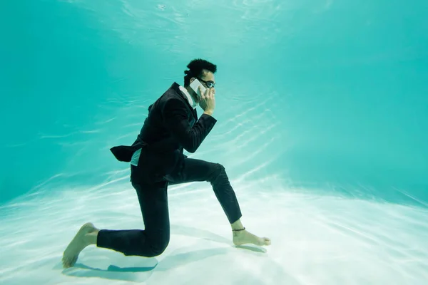 Аравійський бізнесмен в костюмі і гуглі розмовляє по смартфону в басейні — стокове фото