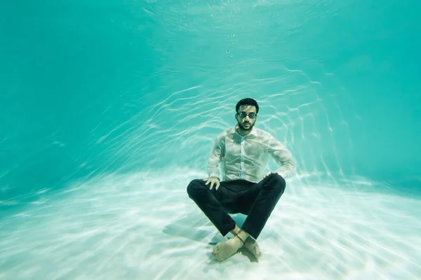 Árabe hombre de negocios nadando con piernas cruzadas en la piscina - foto de stock