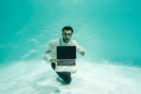 Empresário árabe incrível apontando para laptop com tela em branco subaquático na piscina — Fotografia de Stock