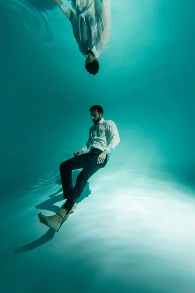 Hombre de negocios árabe nadando cerca del fondo de la piscina - foto de stock