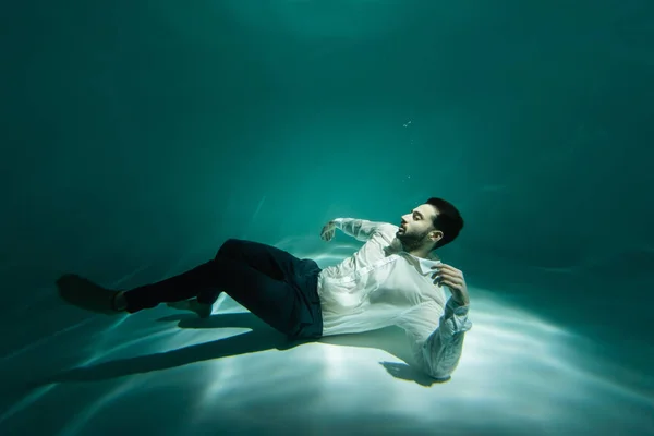 Hombre de negocios musulmán nadando bajo el agua en la piscina - foto de stock