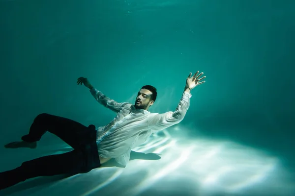 Аравійський бізнесмен плаває в басейні з світлом. — стокове фото