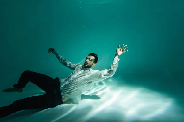 Arabian businessman swimming in pool with light — Stock Photo