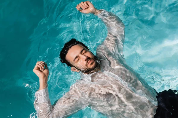 Blick von oben auf den arabischen Geschäftsmann, der im Pool schwimmt — Stockfoto