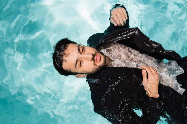Vista superior del hombre de negocios árabe en traje de baño en piscina con luz - foto de stock