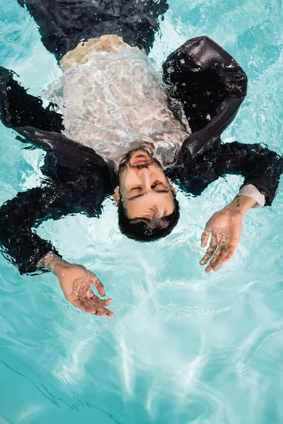 Vista superior del hombre de negocios árabe con los ojos cerrados nadando en la piscina - foto de stock