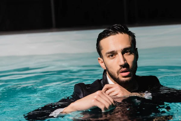 Arabo uomo d'affari in tuta guardando la fotocamera in piscina — Foto stock