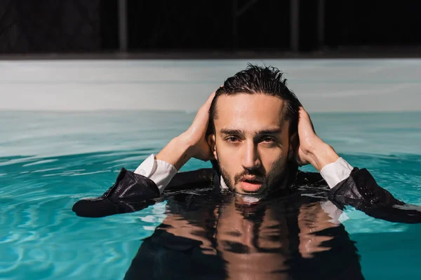 Bärtiger muslimischer Geschäftsmann blickt im Schwimmbad in die Kamera — Stockfoto