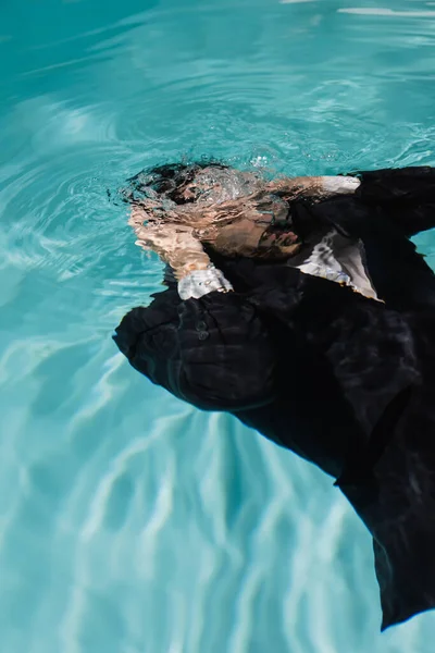 Empresario nadando bajo el agua en piscina con agua turquesa - foto de stock