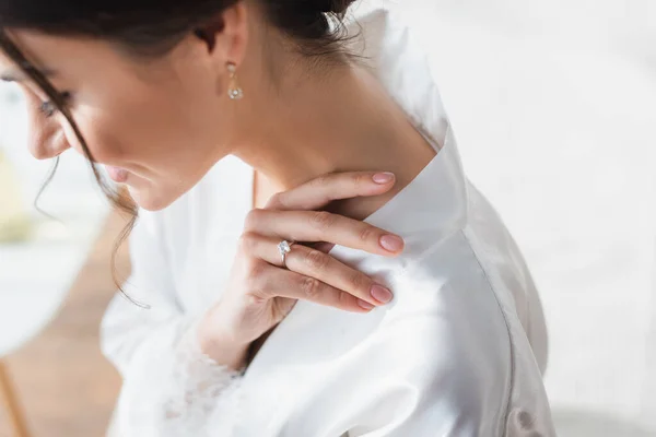 Jovem, noiva sorridente em anel de casamento e roupão de cetim branco — Fotografia de Stock