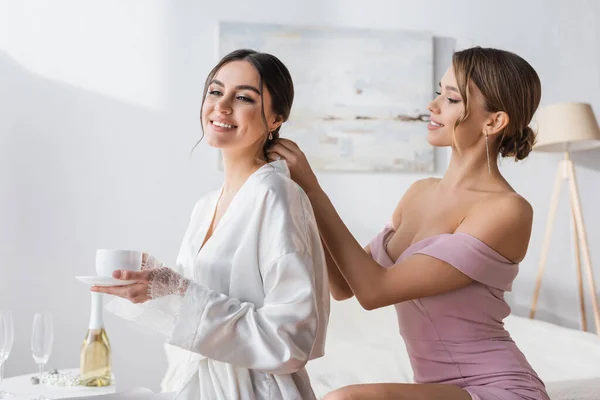 Jolie femme faisant coiffure à mariée heureuse en robe de soie — Photo de stock