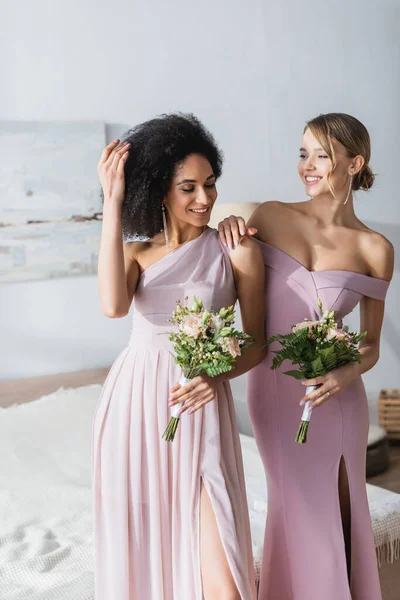 Elegante africana americana mujer fijación pelo cerca feliz amigo - foto de stock