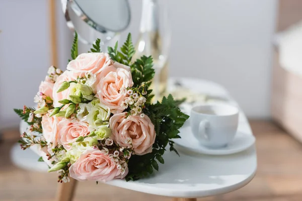 Selective focus of wedding bouquet near coffee cup and mirror on blurred background — Stock Photo