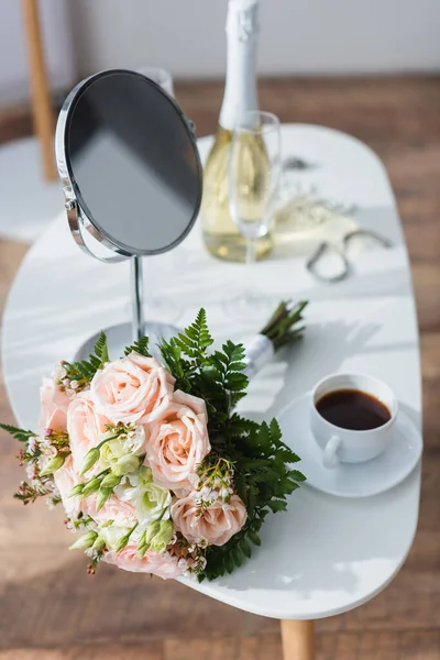 Ramo de boda, espejo y taza de café cerca de botella de champán sobre fondo borroso - foto de stock