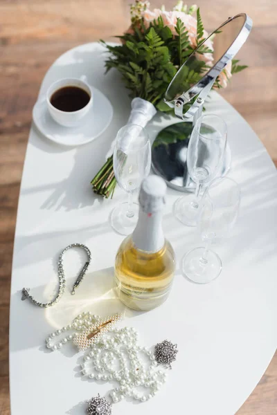 Високий кут зору перлового намиста, шампанського, весільного букета і чашки на кавовому столі — стокове фото