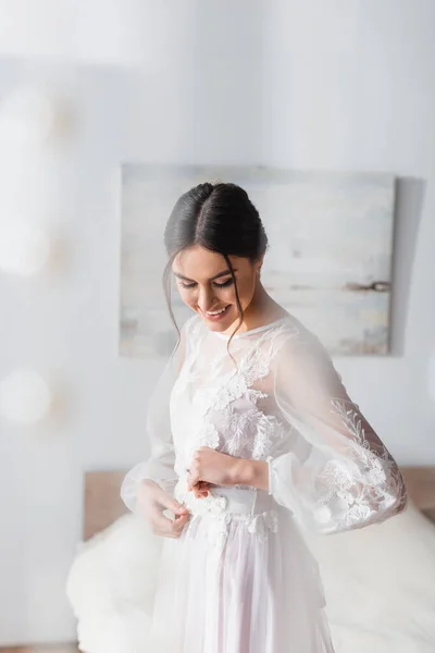 Усміхнений, брюнетка наречена в білій весільній сукні на розмитому фоні — стокове фото
