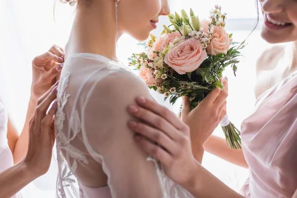 Обрізаний вид подружок нареченої, що готують усміхнену наречену на весілля, розмитий передній план — стокове фото