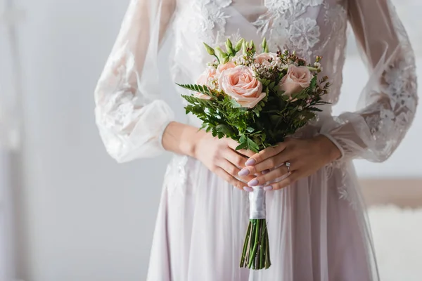 Cropped view of bride in white dress with wedding bouquet — Stock Photo