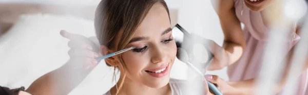 Damas de honor aplicando maquillaje en la novia bonita, primer plano borrosa, pancarta - foto de stock