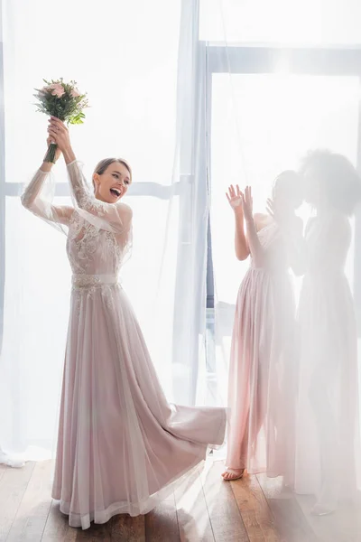 Mariée excitée lancer bouquet de mariage près demoiselles d'honneur — Photo de stock