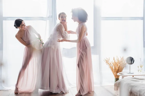 African american woman pointing with hand near excited bride and bridesmaid — Stock Photo